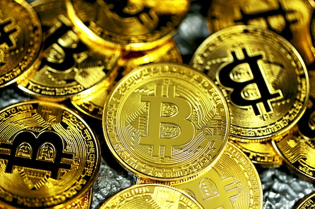 A pile of scattered Bitcoin coins on a silver surface